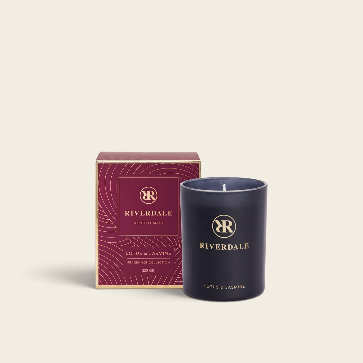 Riverdale Lotus & Jasmine scented candle in a burgundy glass jar with gold logo next to its matching gift box.