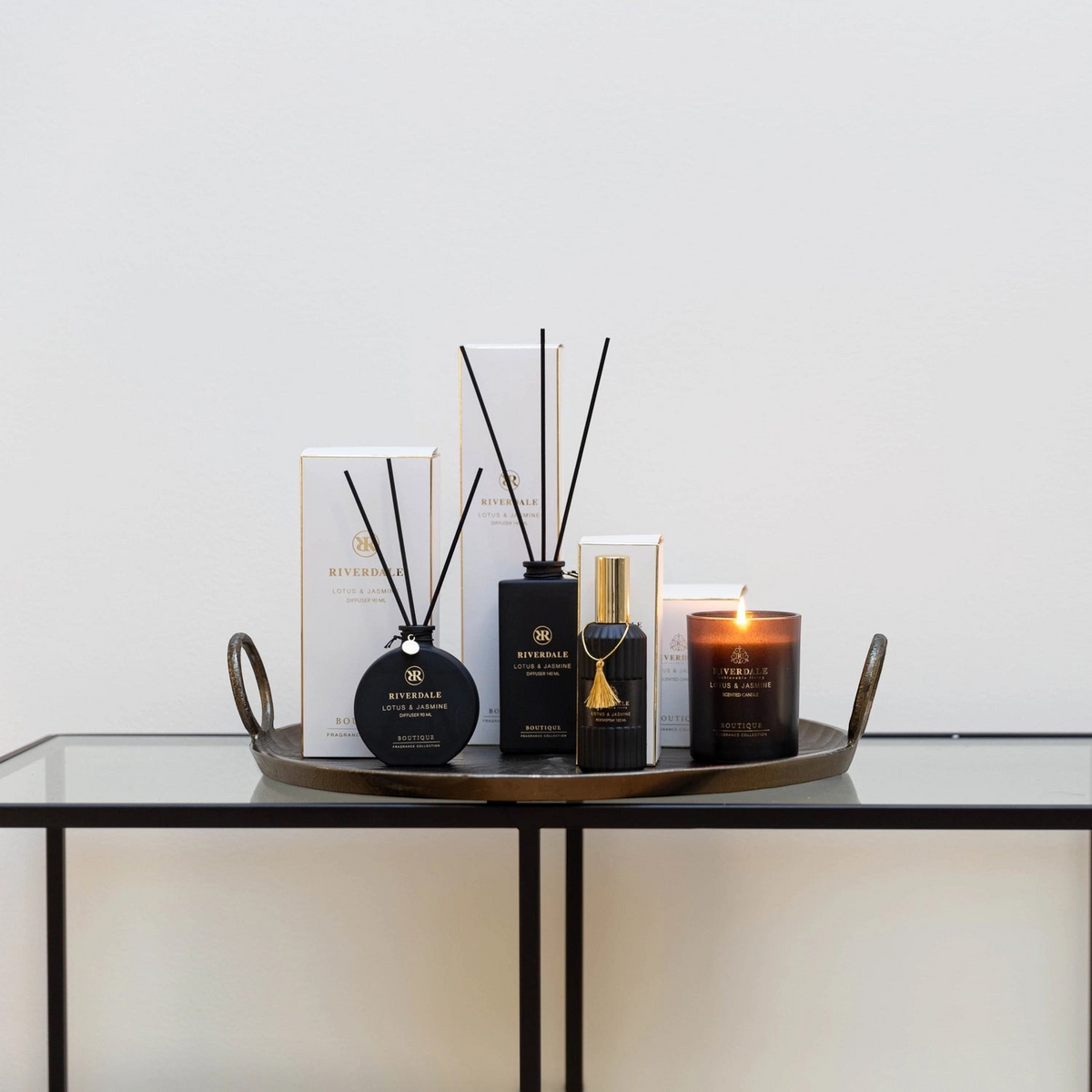 Riverdale Lotus & Jasmine fragrance collection featuring diffusers, roomspray, and scented candle on a metal tray.