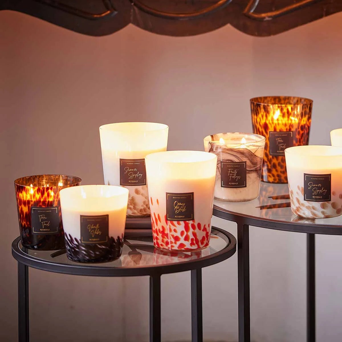 Riverdale Sense scented candles in decorative glass jars with leopard print and abstract patterns on a side table