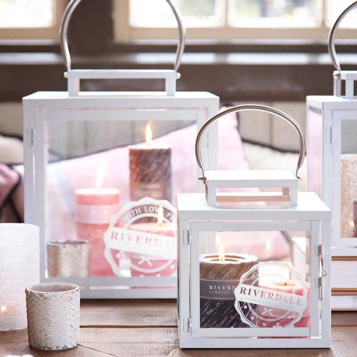 Riverdale Swirl Arabian Nights dark grey scented pillar candle inside a white metal lantern on a wooden table