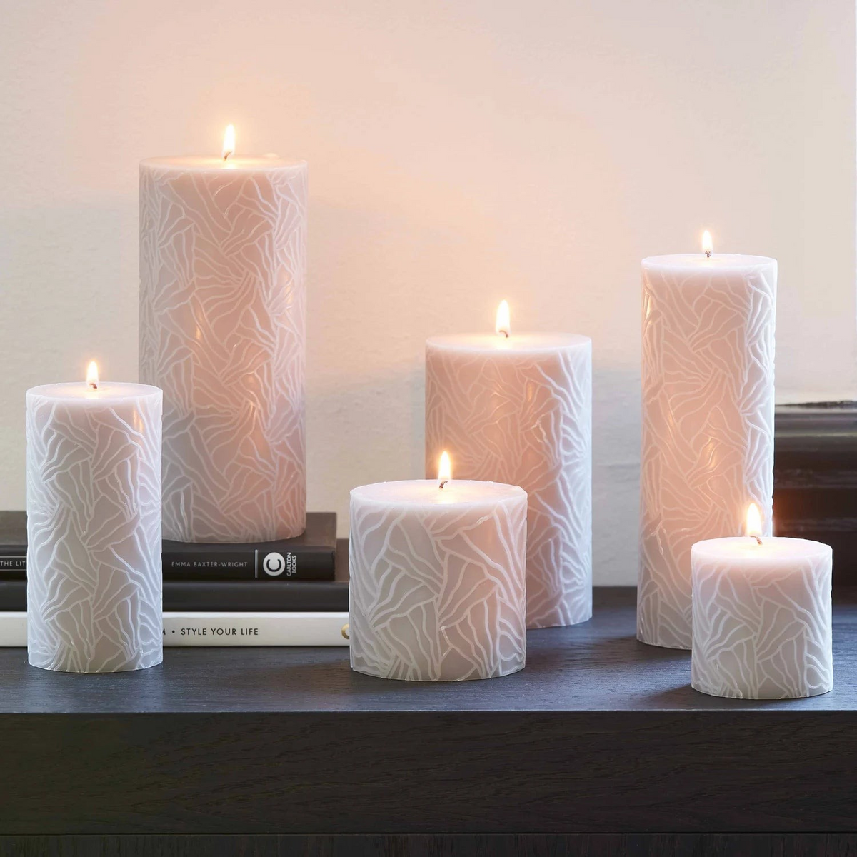 Riverdale light grey pillar candles with a textured wave pattern arranged on a dark shelf for a cozy atmosphere
