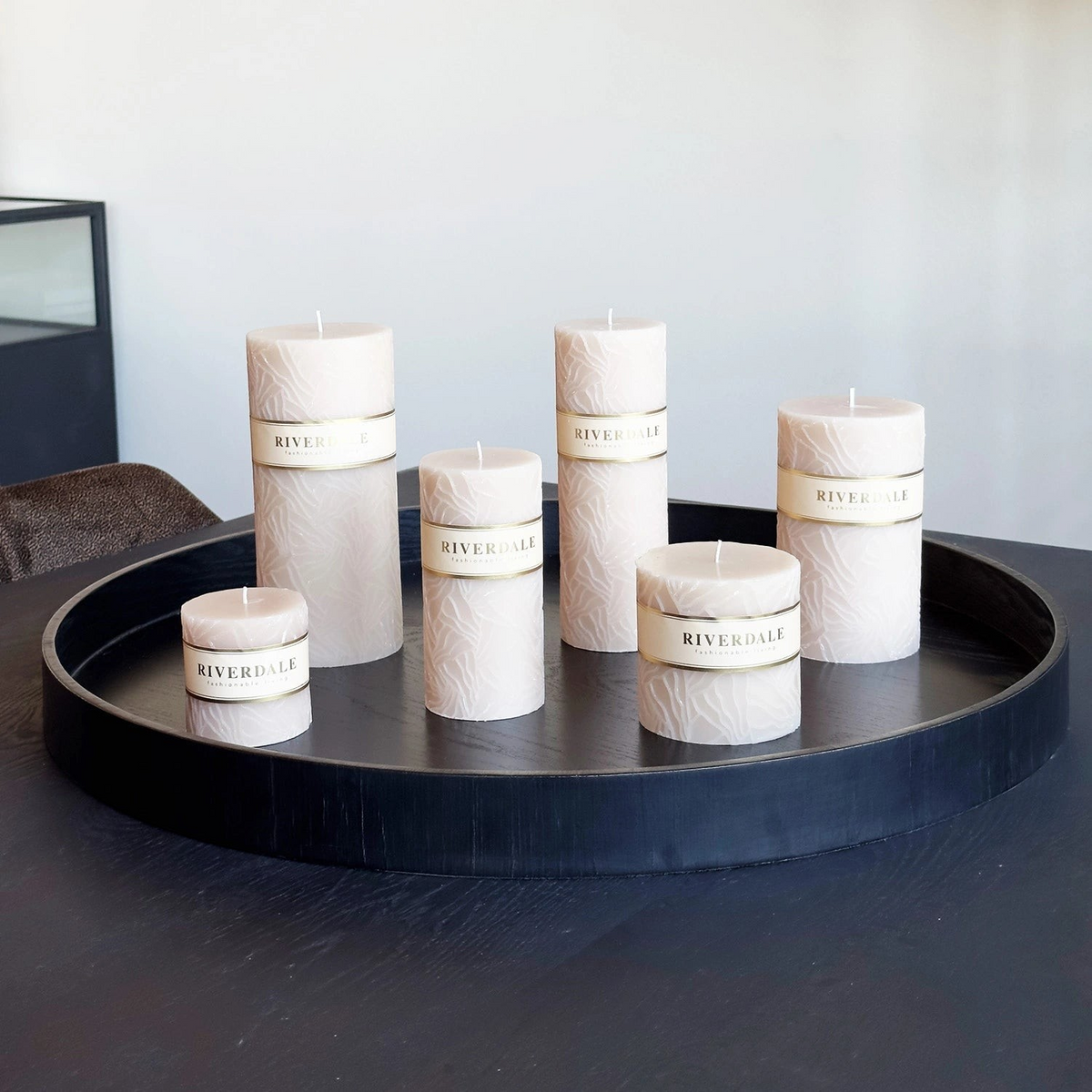 Riverdale sand-colored Wave pillar candles with textured oyster mushroom pattern arranged on a black round tray